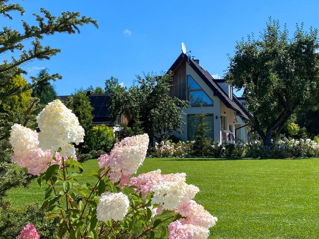 a house with flowers in front of a yard at Osada Białka Tatrzańska - apartamenty & domki z ogrodem dla rodzin, Odkryj-Bialke in Białka Tatrzańska