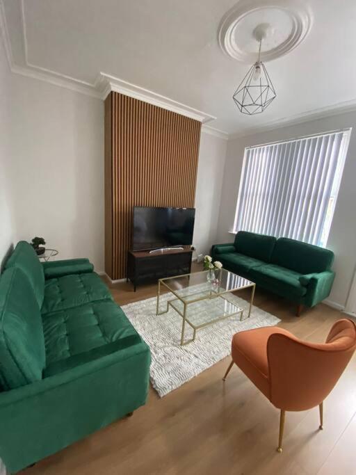 a living room with a green couch and a table at 3-Bed House Near M1 & Meadowhall with Free Parking in Sheffield