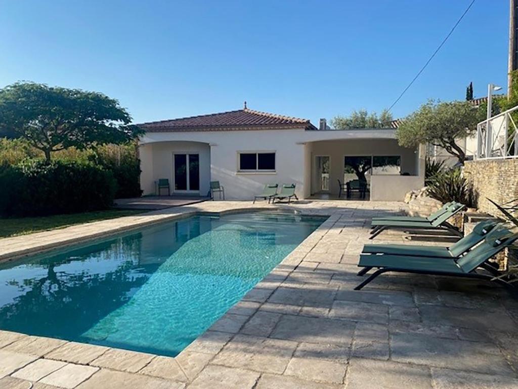 une piscine avec deux chaises et une maison dans l'établissement Villa de Pullis, à Poulx
