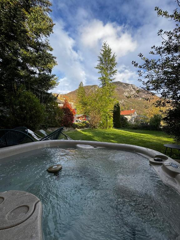 un jacuzzi avec des rochers au milieu d'une cour dans l'établissement Villa & Appartments des Muriers - 500 m du Lac, à Annecy