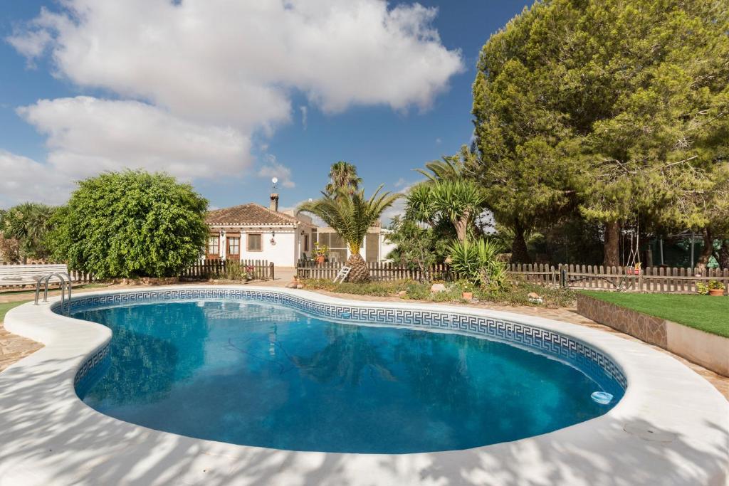 a swimming pool in front of a house with trees at Casa De La Cuesta in Murcia