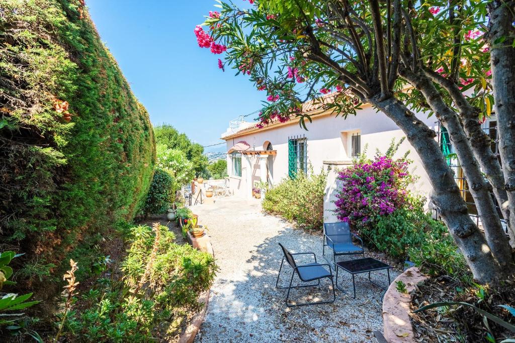 un jardin avec deux chaises et une maison avec des fleurs dans l'établissement VILLA CECILE VI4419 By Riviera Holiday Homes, à Nice
