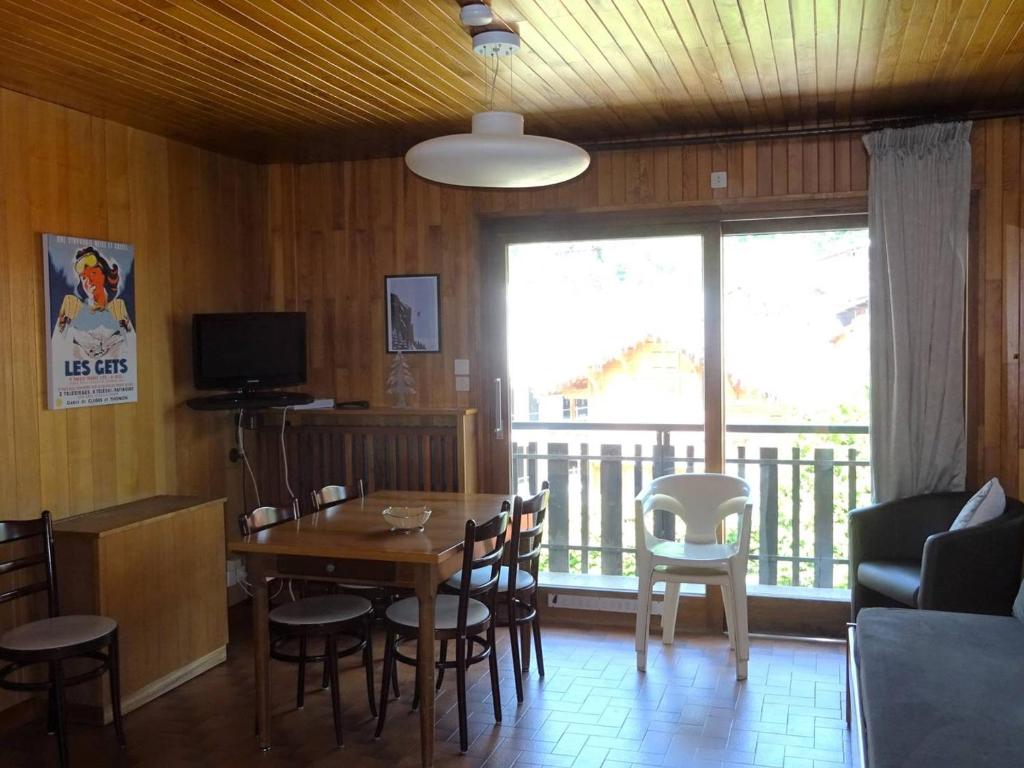 une salle à manger avec une table et des chaises et une grande fenêtre dans l'établissement Les Gets: Appartement 2P, 4 pers. Centre, WiFi, Draps/Serviettes inclus, Proche Commerces et ESF - FR-1-802-15, aux Gets