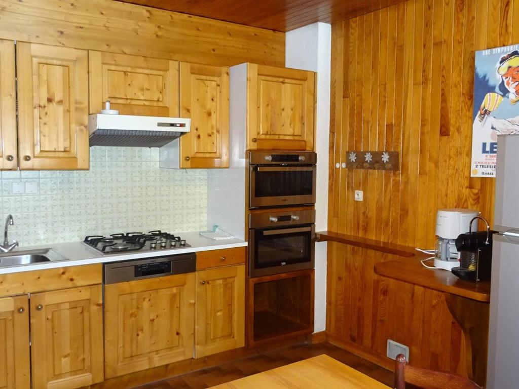 une cuisine avec des armoires en bois et un four à plaques de cuisson dans l'établissement Spacieux 3 pièces central aux Gets - 6 pers, garage, WiFi, draps et serviettes inclus - FR-1-802-25, aux Gets