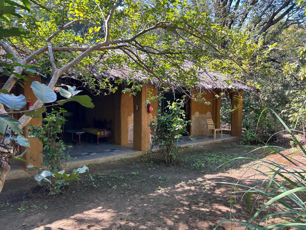 a small house with a table and a tree at Kamp Kamouflage Kanha in Kānha