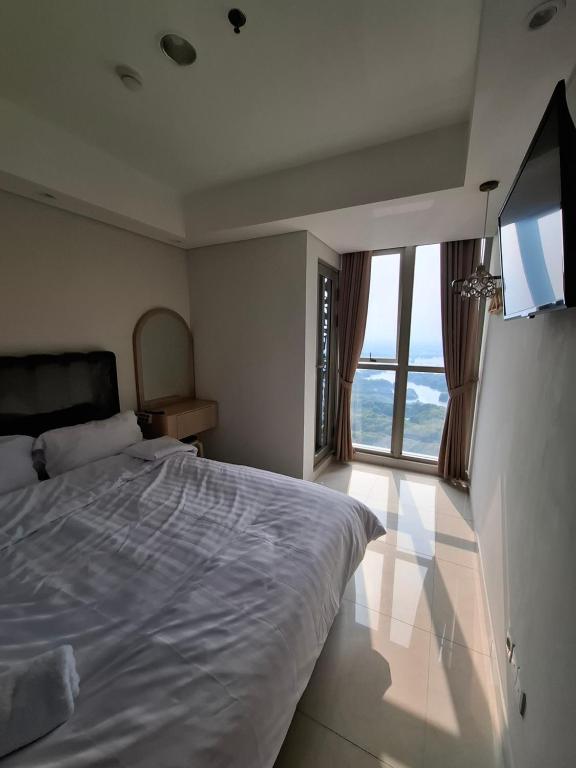 ein Schlafzimmer mit einem großen Bett und einem großen Fenster in der Unterkunft Seaview gold coast pik bisnis room in Jakarta