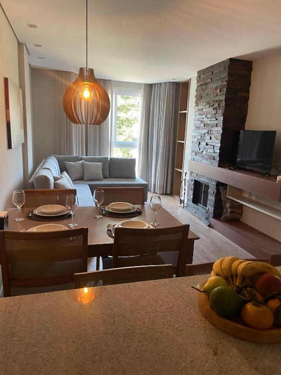 a living room with a table and a living room with a fireplace at Lindo Flat no Serra Class com Piscina e Sauna in Canela