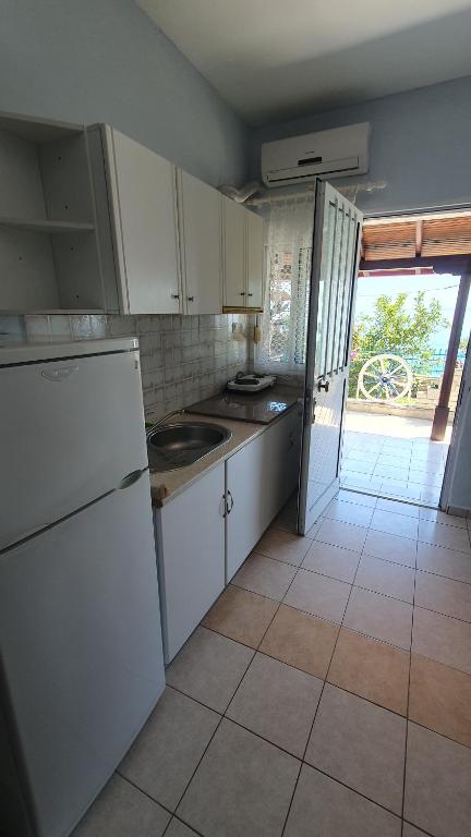 eine Küche mit weißen Geräten und Fliesenboden in der Unterkunft NIKOS SEA VIEW ROOM in Kallithea (Chalkidiki)