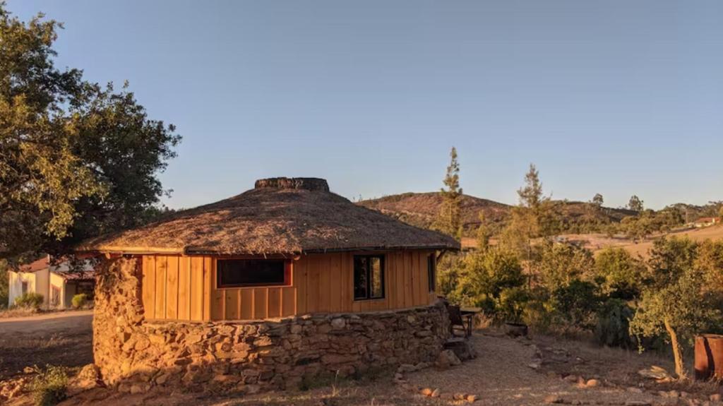 a small stone building with a thatched roof at Eco Roundhouse Quinta Carapeto in São Luis