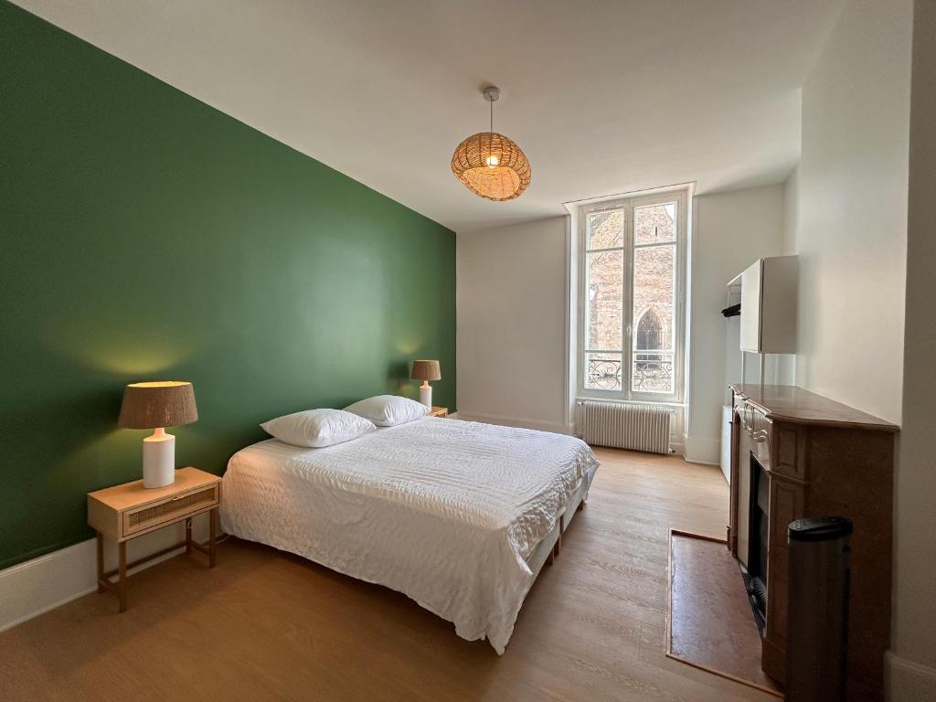 a bedroom with a bed and a green wall at Chez Romain - Appartement au coeur de Meursault in Meursault