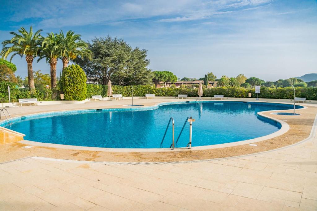 - une grande piscine bordée d'arbres et de palmiers dans l'établissement Studio Cannes Marina Jean Bart, à Mandelieu-la-Napoule