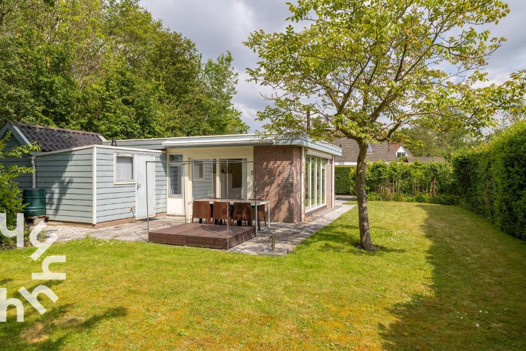 a small house with a table in a yard at Vrijstaande vakantiewoning dichtbij het Veerse Meer in Wolphaartsdijk