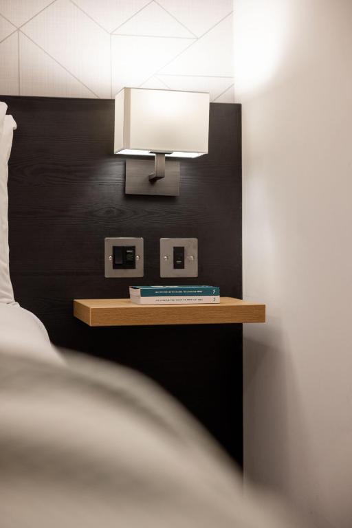 a table with a lamp on a black wall at St Giles London – A St Giles Hotel in London
