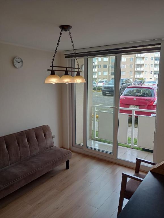 a living room with a couch and a large window at Departamento nuevo 3 dormitorios, Temuco in Temuco