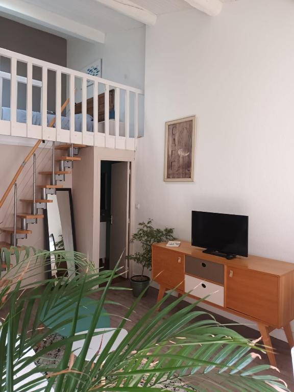 un salon avec une télévision et un escalier dans l'établissement Jolie appartement centre Palavas les Flots, à Palavas-les-Flots