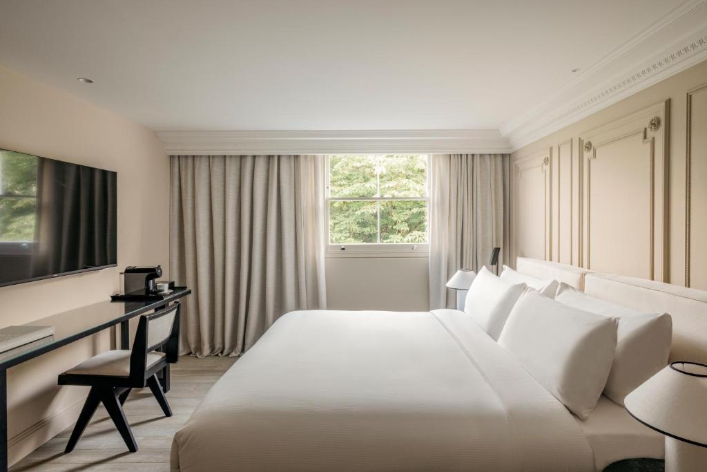 a hotel room with a large white bed and a desk at The Caesar Hotel in London