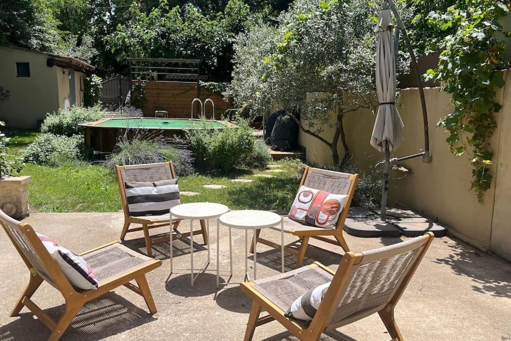 une terrasse avec 3 chaises, une table et un parasol dans l'établissement écrin de verdure, à Saint-Rémy-de-Provence