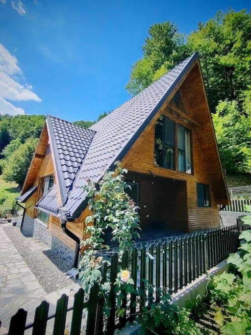 a wooden house with a fence in front of it at Cabana A Brezoi in Brezoi