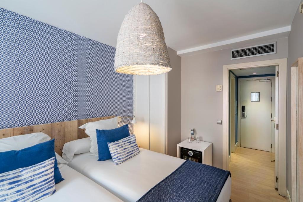 a bedroom with a bed with blue and white pillows at Vincci Puertochico in Santander