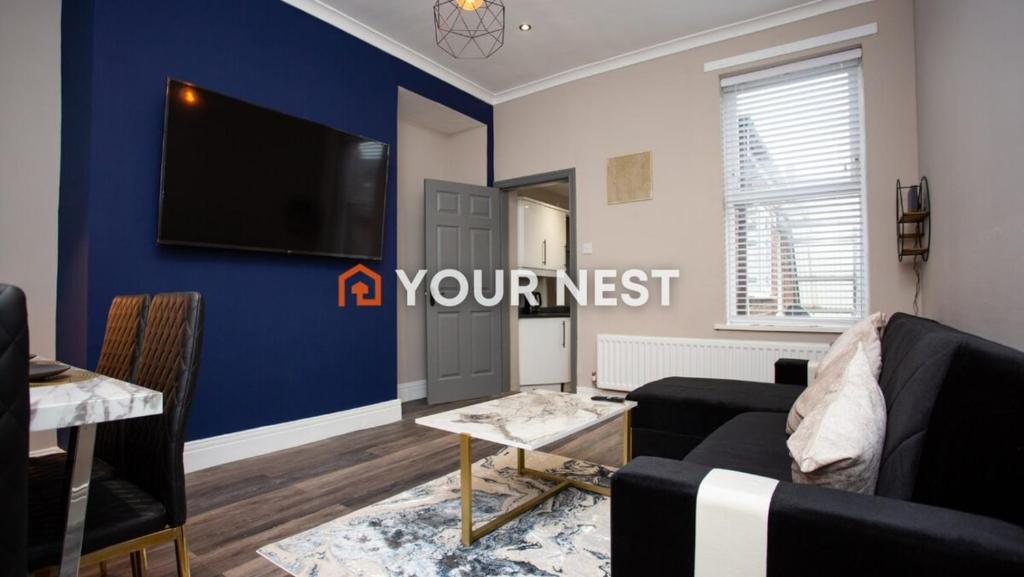 a living room with a couch and a tv on a blue wall at Modern Interior Spacious Four Bedroom Apartment in Westoe