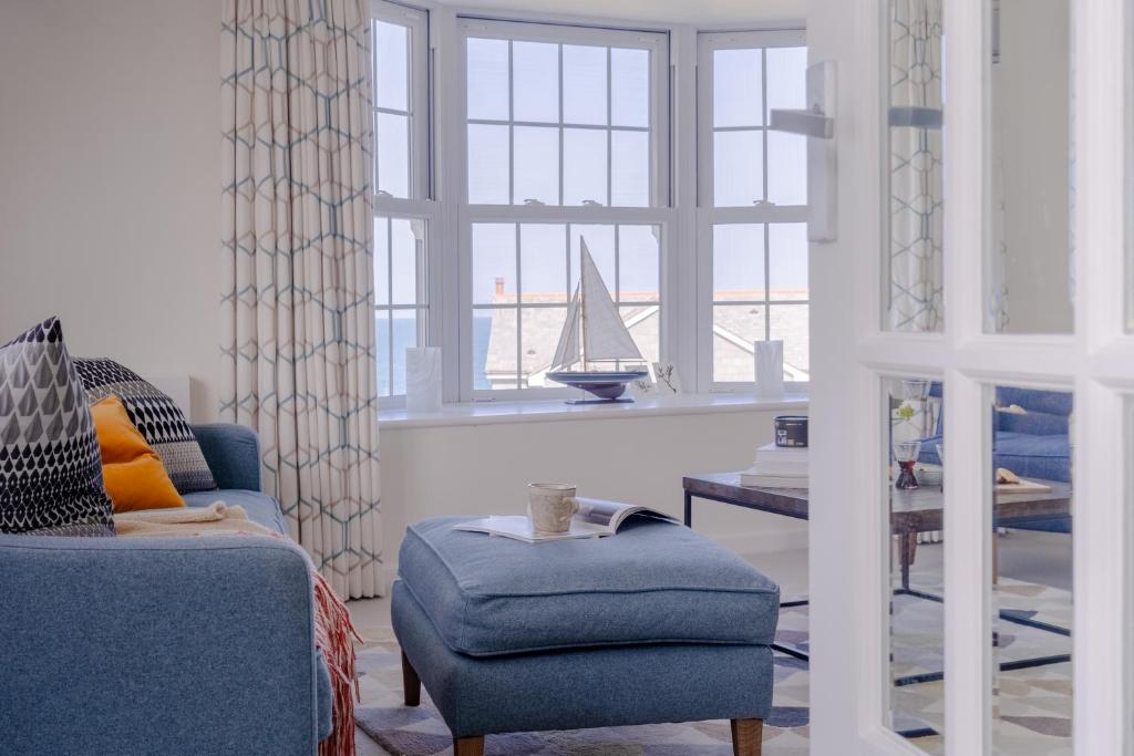 a living room with a blue chair and a sailboat in a window at Sandpipers, Port Isaac Bay Holidays in Port Isaac