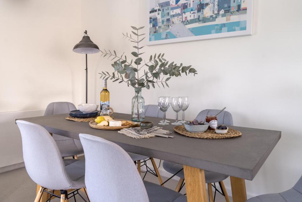 a dining room table with chairs and a table with wine glasses at Sandpipers, Port Isaac Bay Holidays in Port Isaac