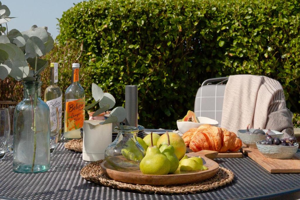 a table with a plate of fruit and wine bottles at Sandpipers, Port Isaac Bay Holidays in Port Isaac
