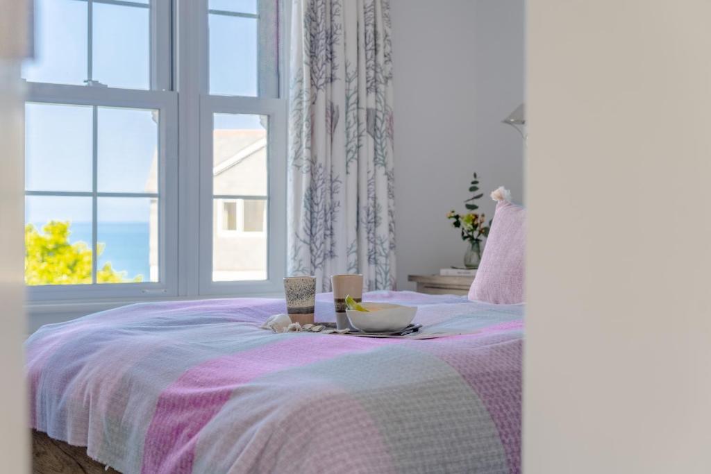 a bedroom with a bed with a purple blanket and a window at Sandpipers, Port Isaac Bay Holidays in Port Isaac