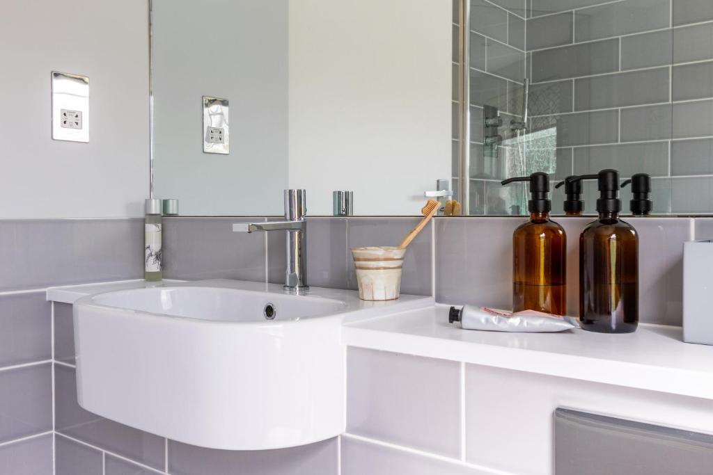 a bathroom with a sink with bottles on a counter at Sandpipers, Port Isaac Bay Holidays in Port Isaac