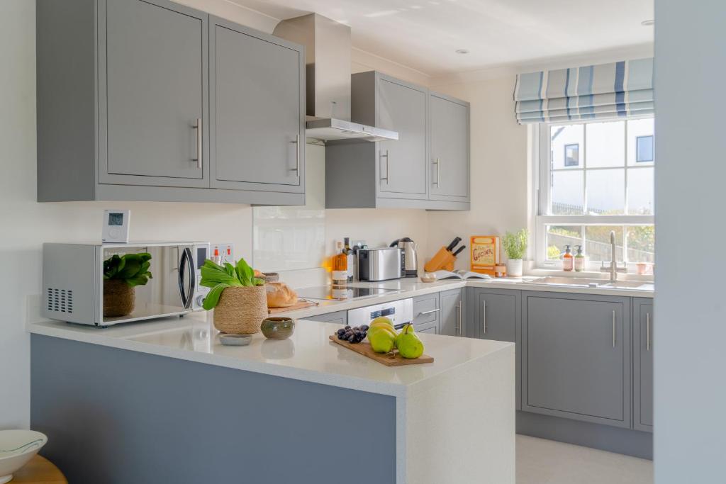 a kitchen with white cabinets and a counter top at Sandpipers, Port Isaac Bay Holidays in Port Isaac
