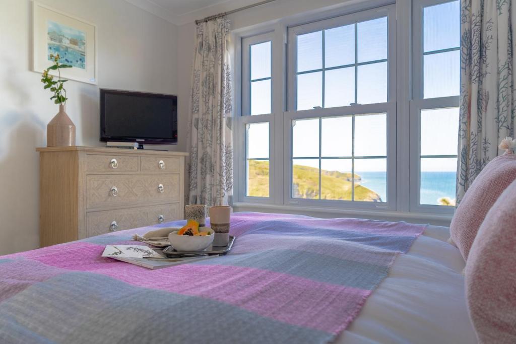 a bed with a tray of food on it with a window at Sandpipers, Port Isaac Bay Holidays in Port Isaac