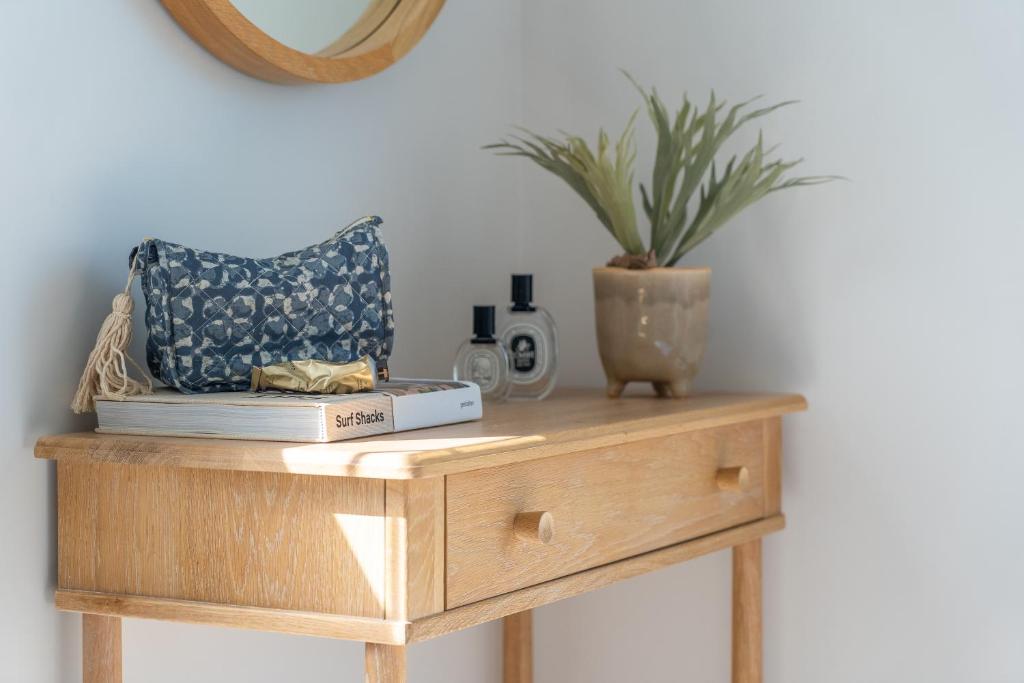 a table with a book and a plant on it at Sandpipers, Port Isaac Bay Holidays in Port Isaac