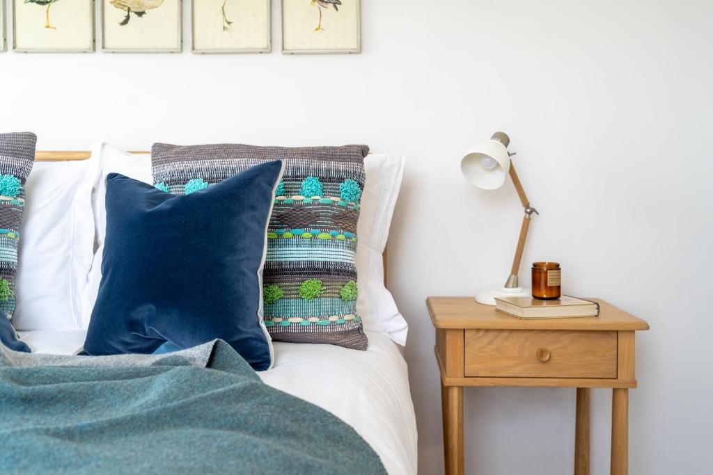 a bed with blue pillows and a lamp on a table at Sandpipers, Port Isaac Bay Holidays in Port Isaac