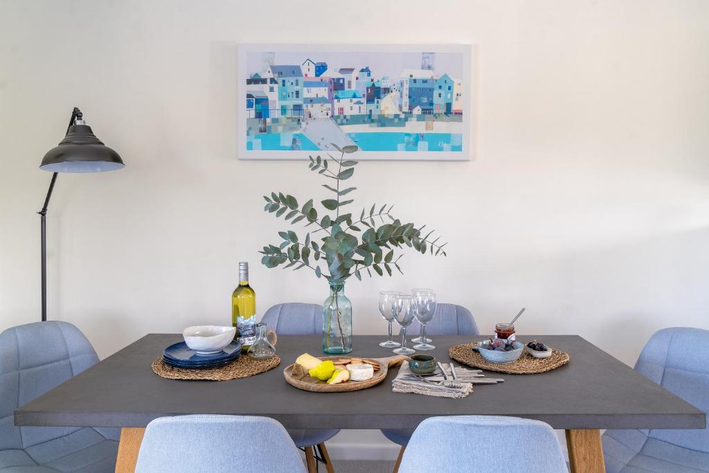 a dining room table with food on it with blue chairs at Sandpipers, Port Isaac Bay Holidays in Port Isaac