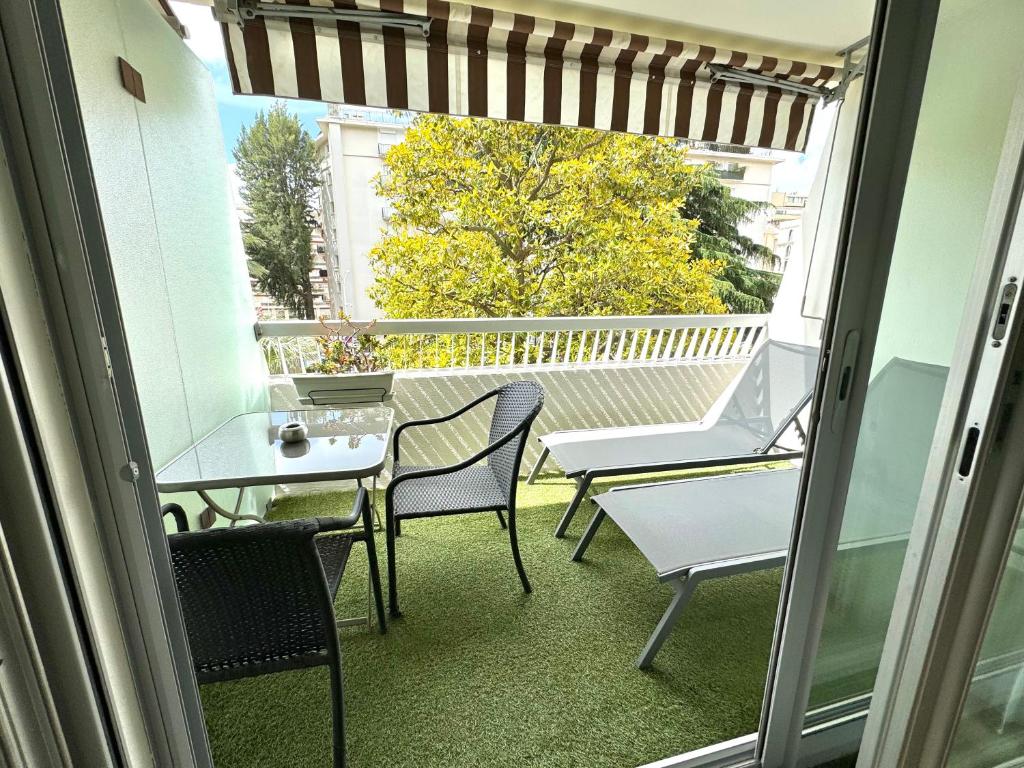 a balcony with a table and chairs and a window at Hôtel Victoria in Cannes