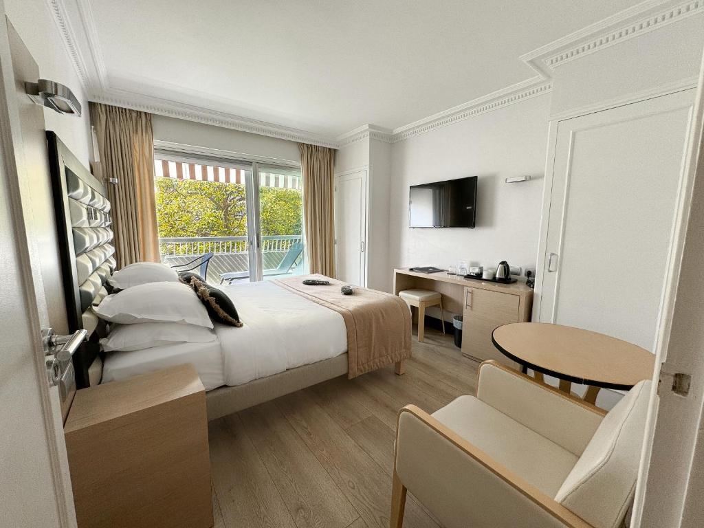 a hotel room with a bed and a desk and a table at Hôtel Victoria in Cannes