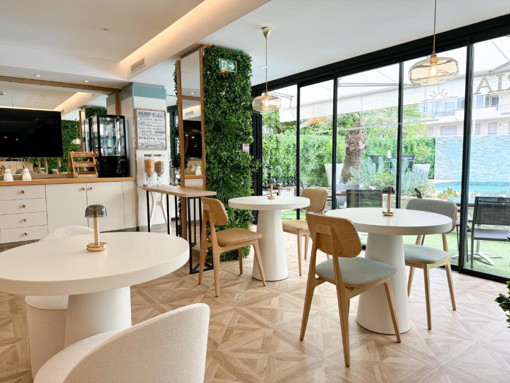 a restaurant with white tables and chairs and windows at Hôtel Victoria in Cannes