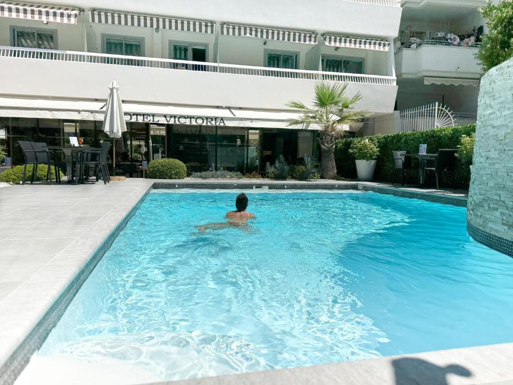 a person in a swimming pool in a hotel pool at Hôtel Victoria in Cannes