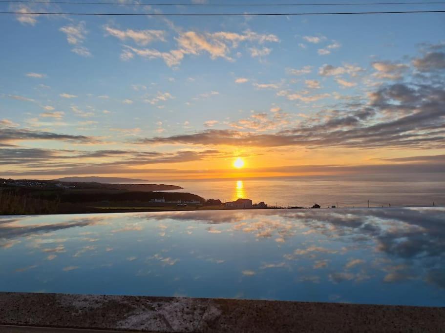 a sunset over the ocean with the sun in the sky at Grandma's House in Achada