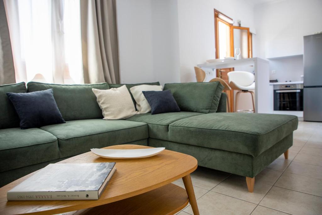 ein Wohnzimmer mit einer grünen Couch und einem Tisch in der Unterkunft Senses Aegina Downtown Residence in Ägina Stadt