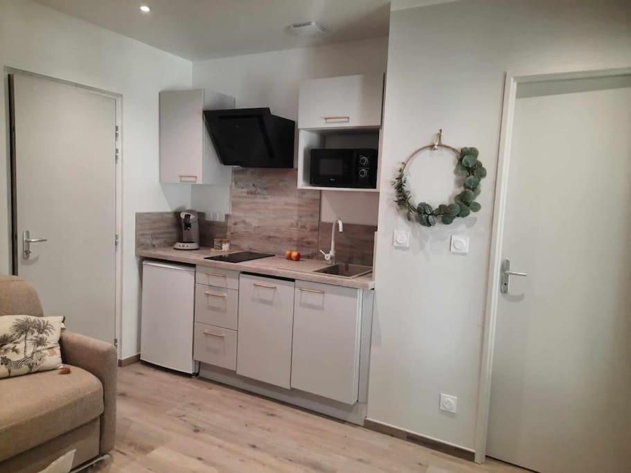 une cuisine avec des armoires blanches et un salon dans l'établissement Studio 3 - Appart' Hôtel tout confort avec balcon - TU ELLETA, à Tulette