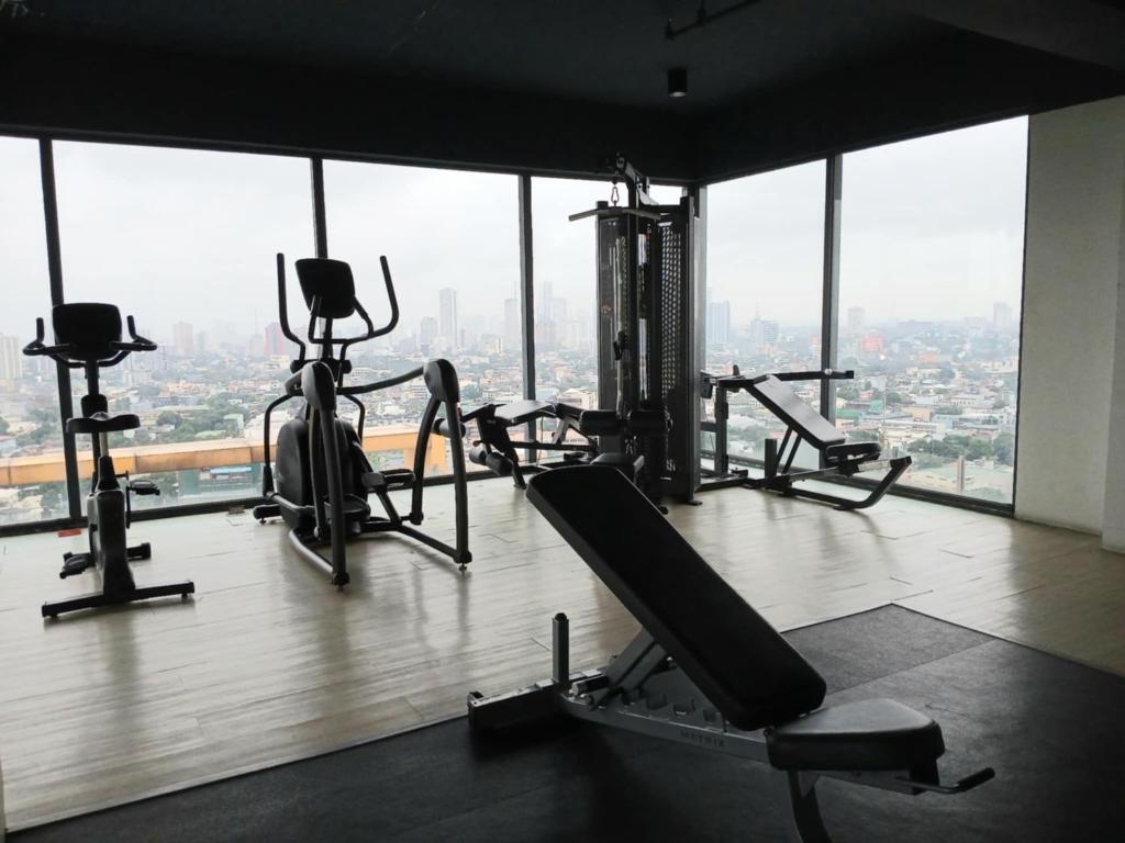 a gym with cardio equipment in a building with windows at Centro Tower - 2 Bedroom Fully Furnished in Manila