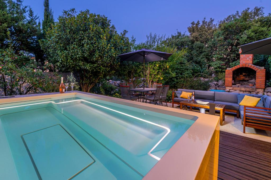 a swimming pool in a backyard with a couch and an umbrella at Apartment with terrace and mini pool Green Gold in Dubrovnik
