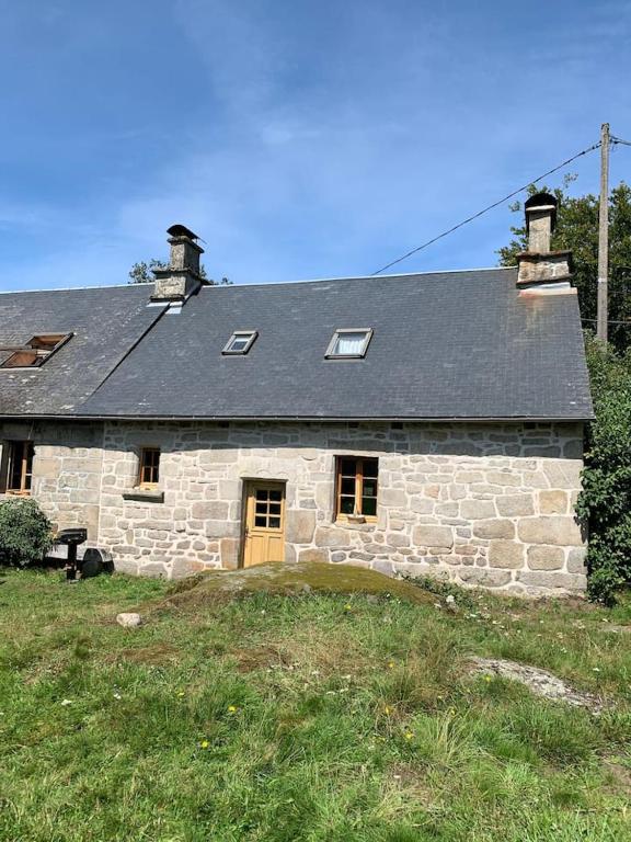 une ancienne maison en pierre avec un toit noir dans l'établissement Maison en granite typique à Chaumeil avec jardin privé., à Chaumeil