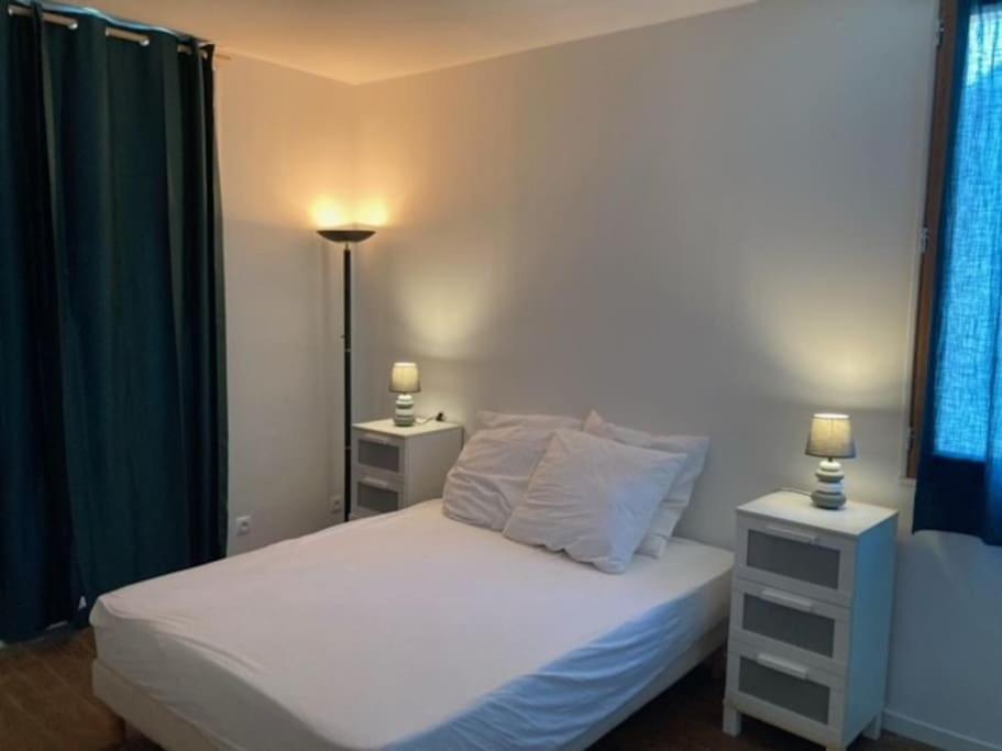 コンカルノーにあるLe Cocon de Renée, Maison atypique en ville close de Concarneauのベッド、ナイトスタンド2台、ランプ2個を備えた寝室