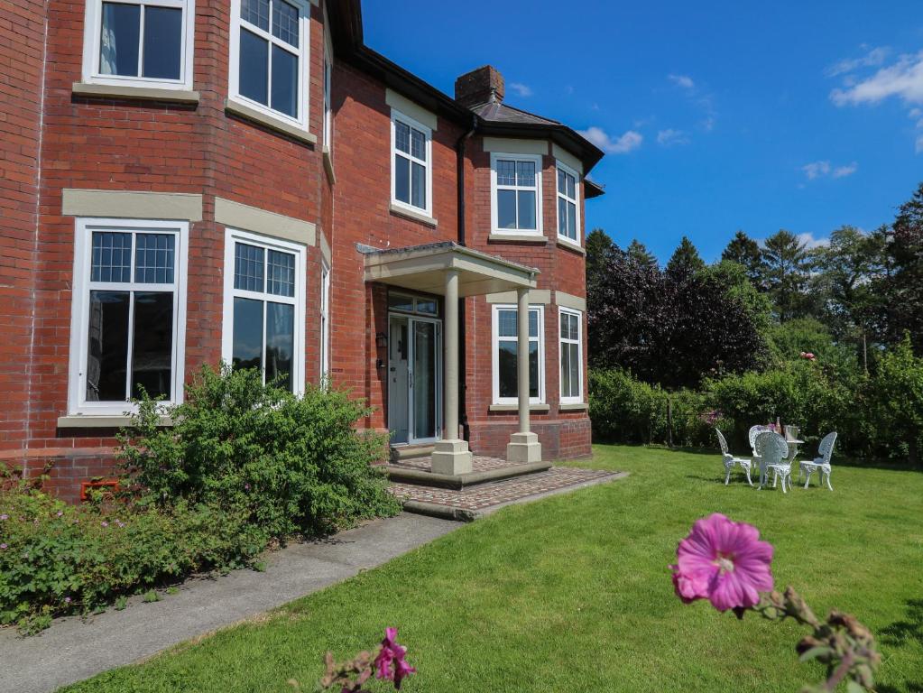 a brick house with a yard with a pink flower at Tirallen in Llanwrda