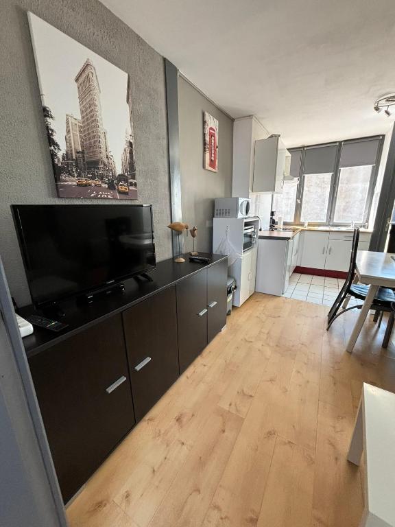 un salon avec une grande télévision et une cuisine dans l'établissement La Sarcelle, à Fort-Mahon-Plage