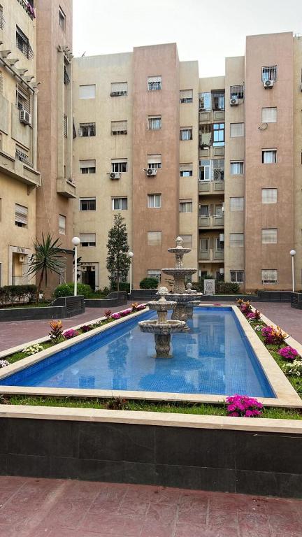 a swimming pool with a fountain in front of a building at Chez Mamie Kenza in Mohammedia