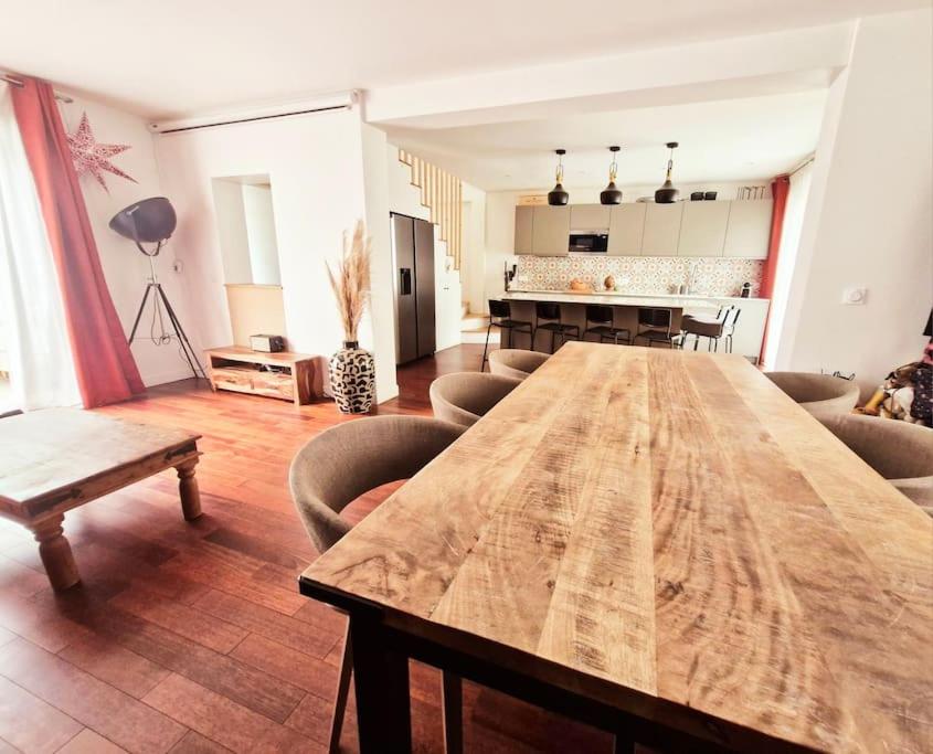 un salon avec une table et des chaises en bois dans l'établissement belle Maison familiale, jardin, à LʼÎle-Saint-Denis
