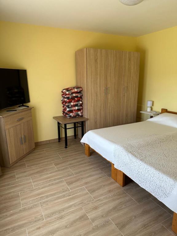 a bedroom with a bed and a tv and a cabinet at Casuta MARI in Săldăbagiu de Munte